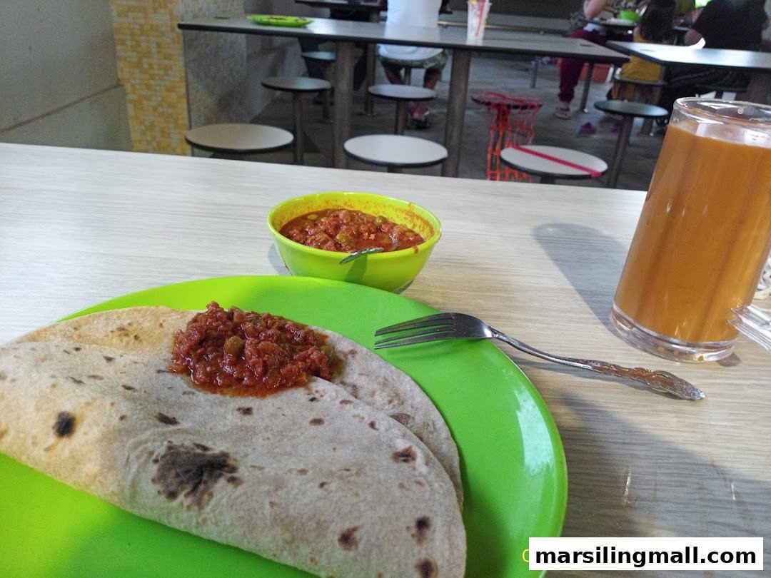 A plate of chapati with curry and a drink on a table in a casual restaurant setting.