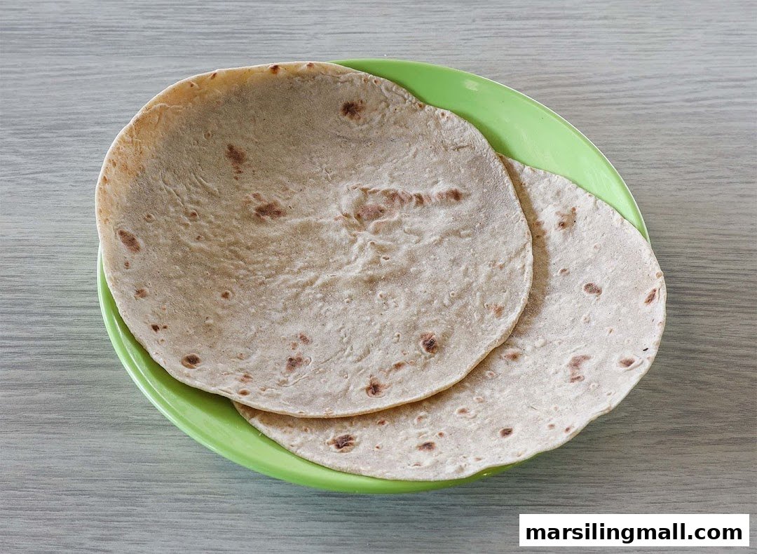 Two freshly made chapatis or flatbreads resting on a vibrant green plate.