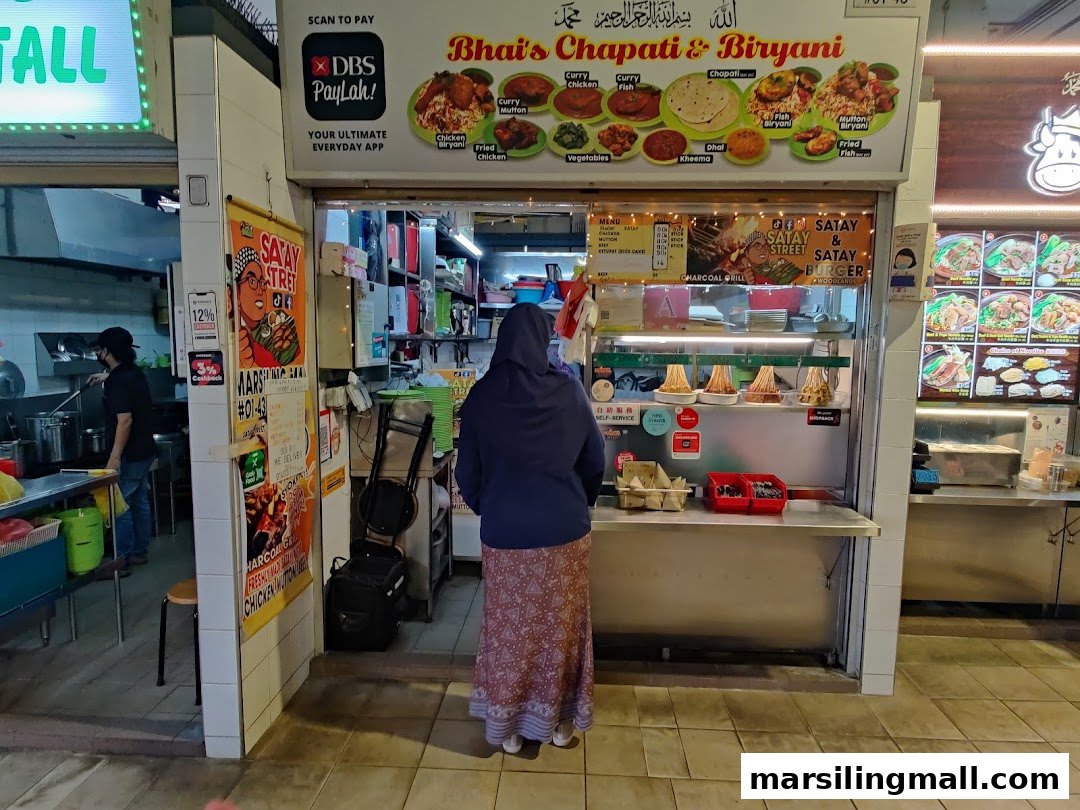 Exterior view of Bhais Chapati & Biryani, showcasing its menu board and a customer at the counter.