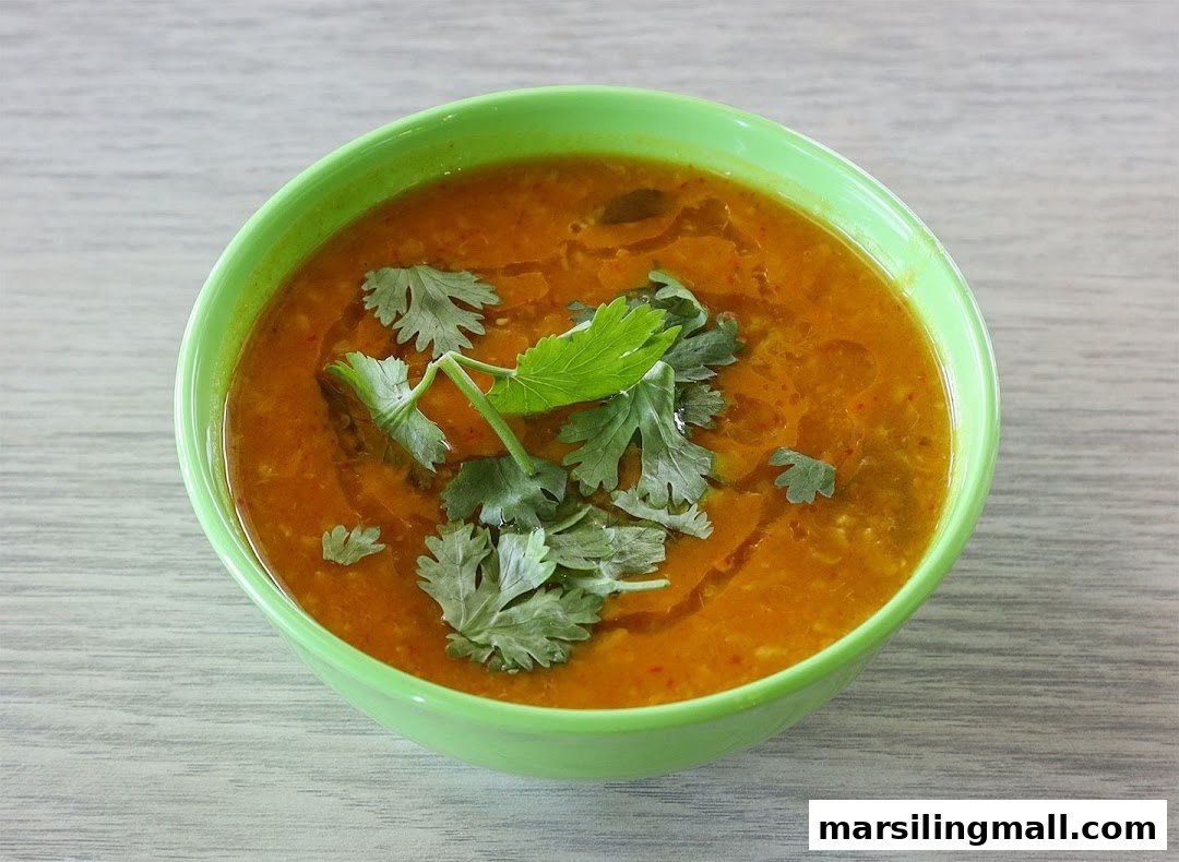A vibrant bowl of lentil soup or curry, garnished with fresh green herbs.
