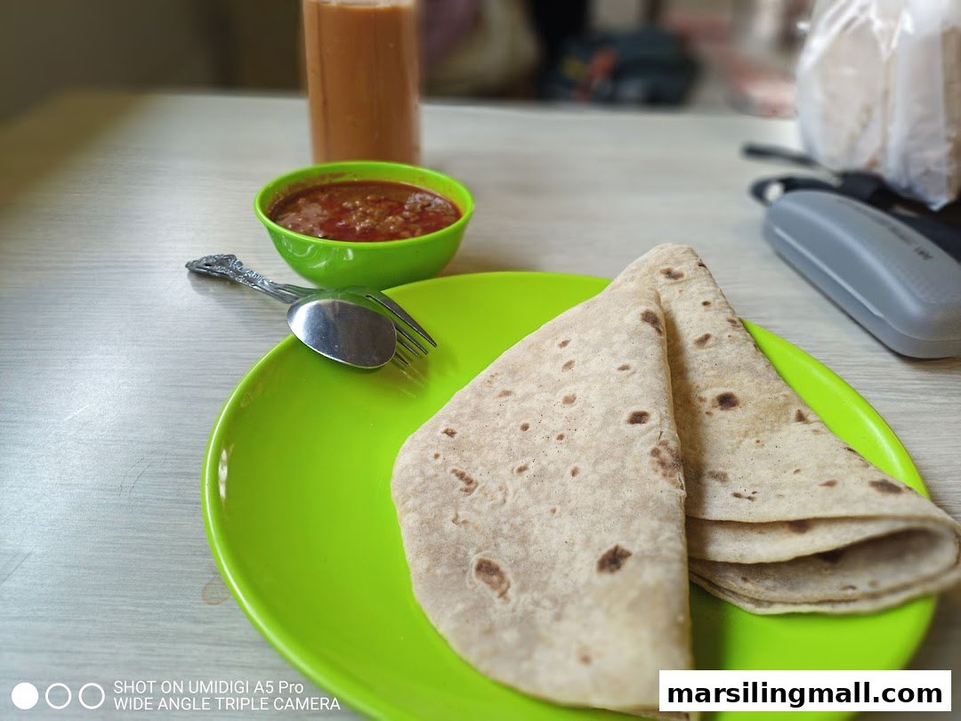 A plate of chapatis with a bowl of curry and a drink on a table.
