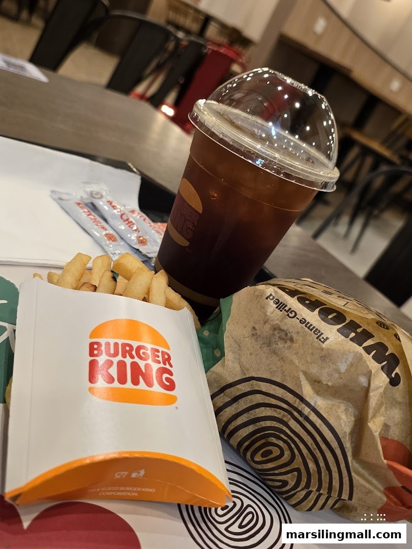 A Burger King meal featuring fries, a drink, and a wrapped burger on a table.