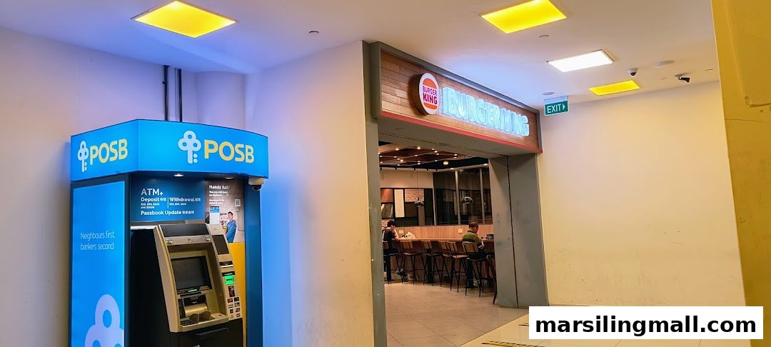 The entrance of Burger King, featuring its illuminated sign, next to a POSB ATM.