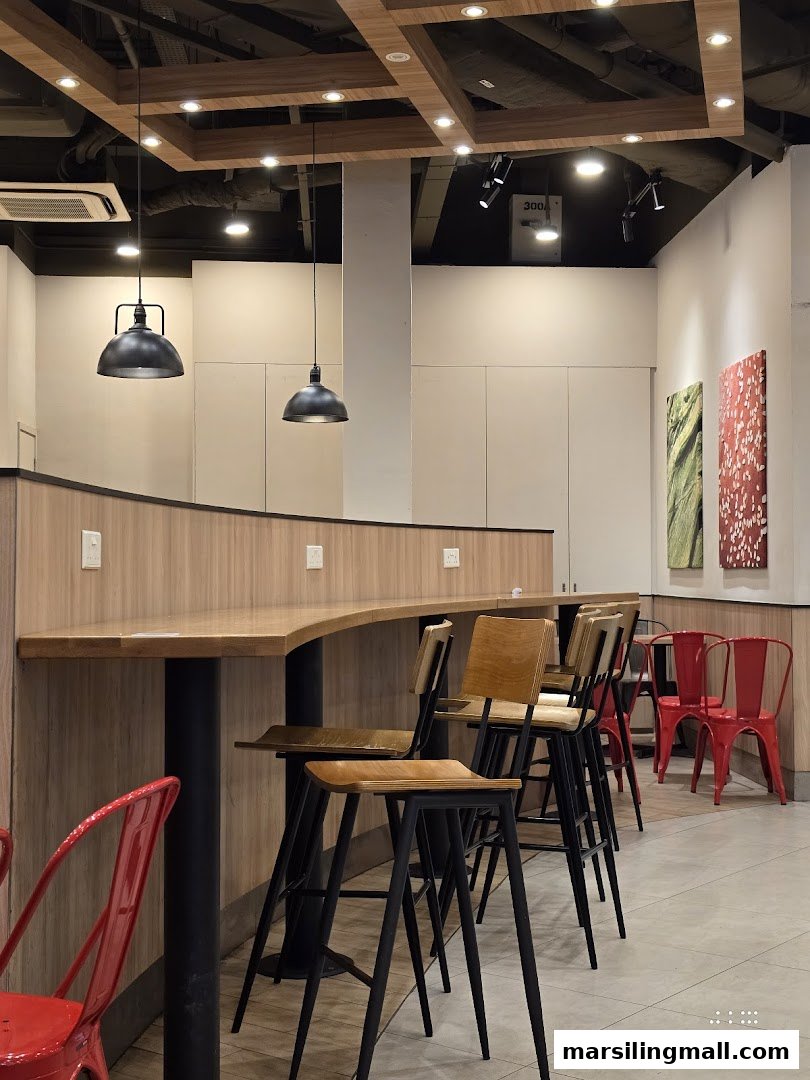 Interior view of Burger King with modern seating, bar stools, and red chairs.
