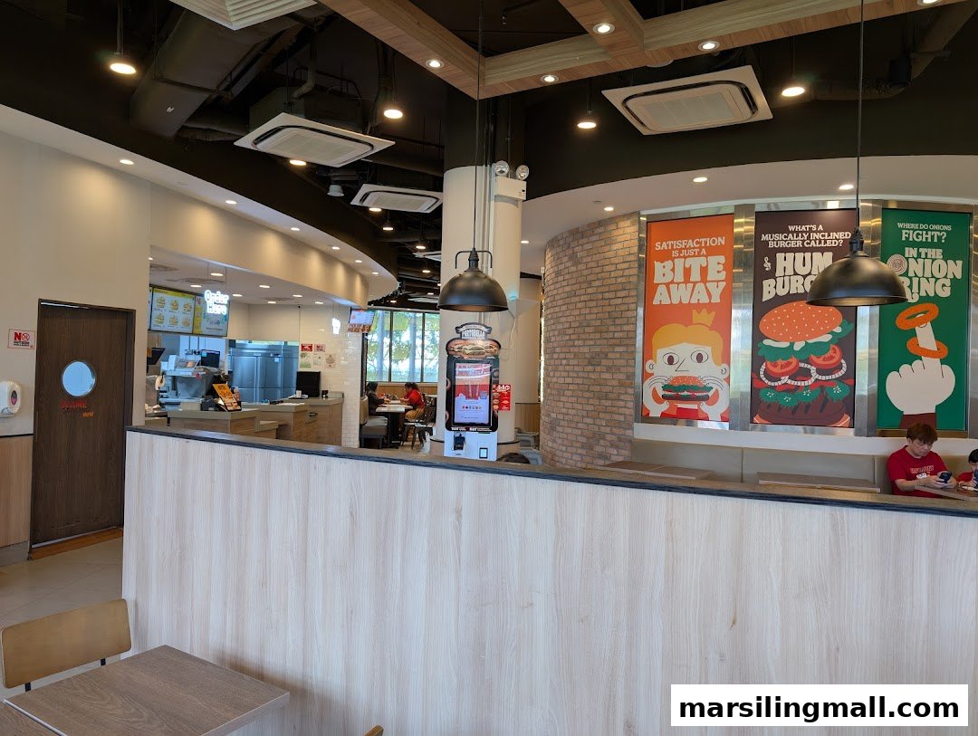 Interior view of a Burger King restaurant showing the counter, seating area, and promotional posters.