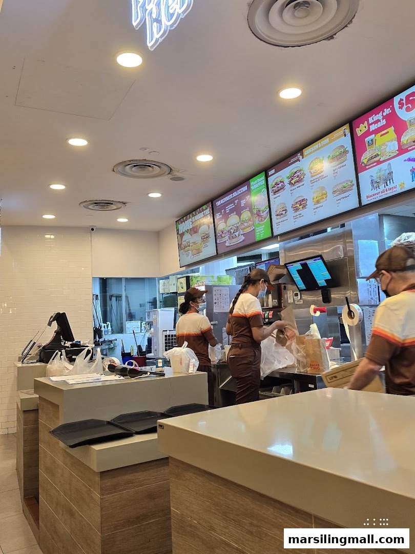 Interior view of Burger King showing staff preparing orders at the counter with digital menu boards above.