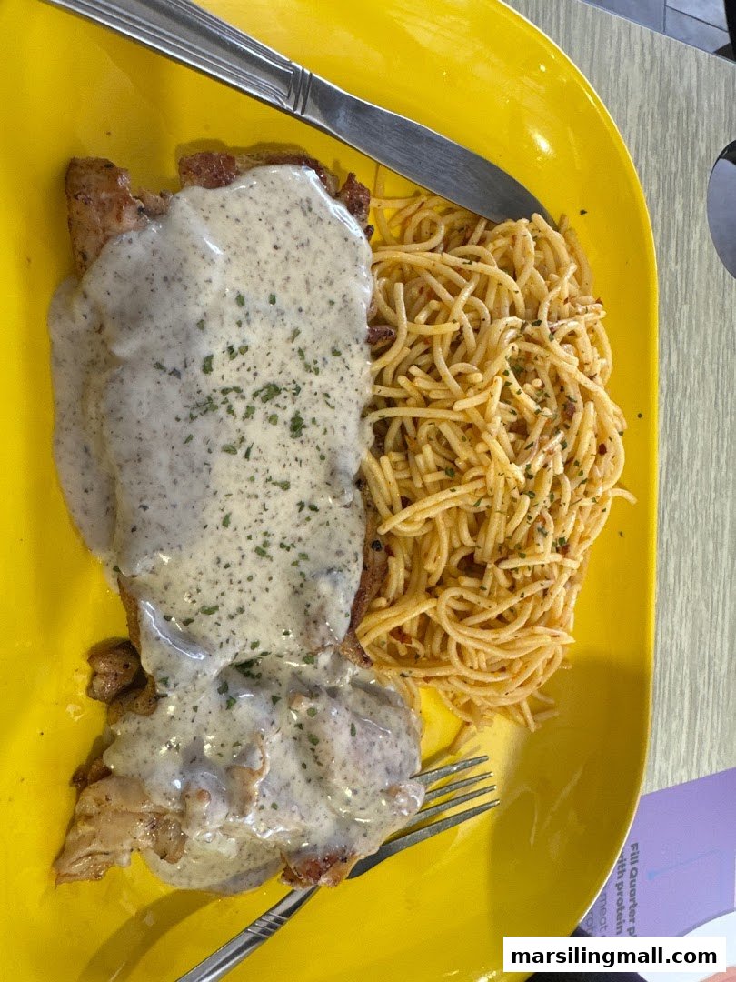 A vibrant yellow plate featuring chicken with creamy sauce and a side of spaghetti.