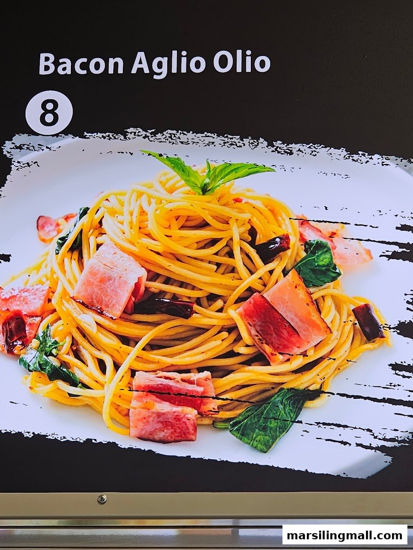 A close-up of a delicious Bacon Aglio Olio pasta dish displayed on a menu board.
