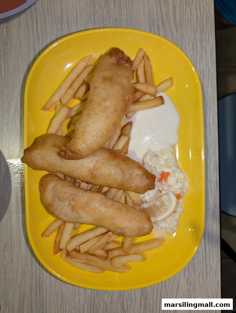 A vibrant yellow plate holds golden-brown fish and chips with coleslaw and tartar sauce.
