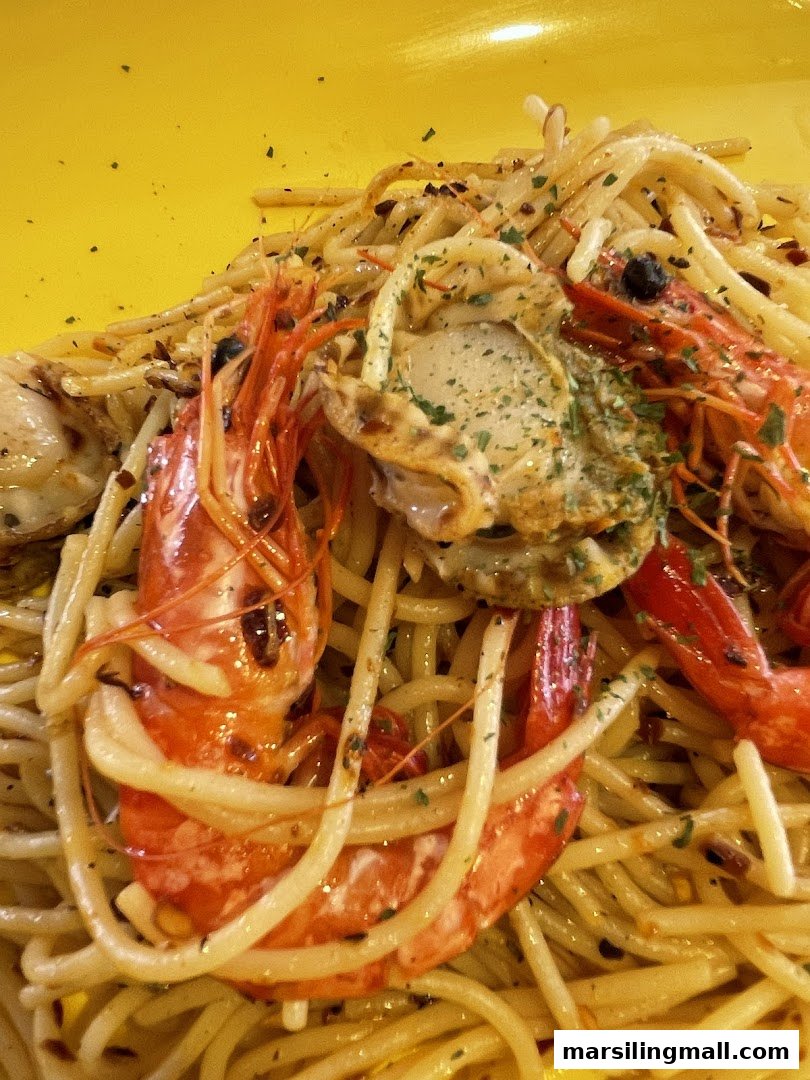 A vibrant close-up of seafood pasta featuring large prawns and a scallop on a yellow plate.