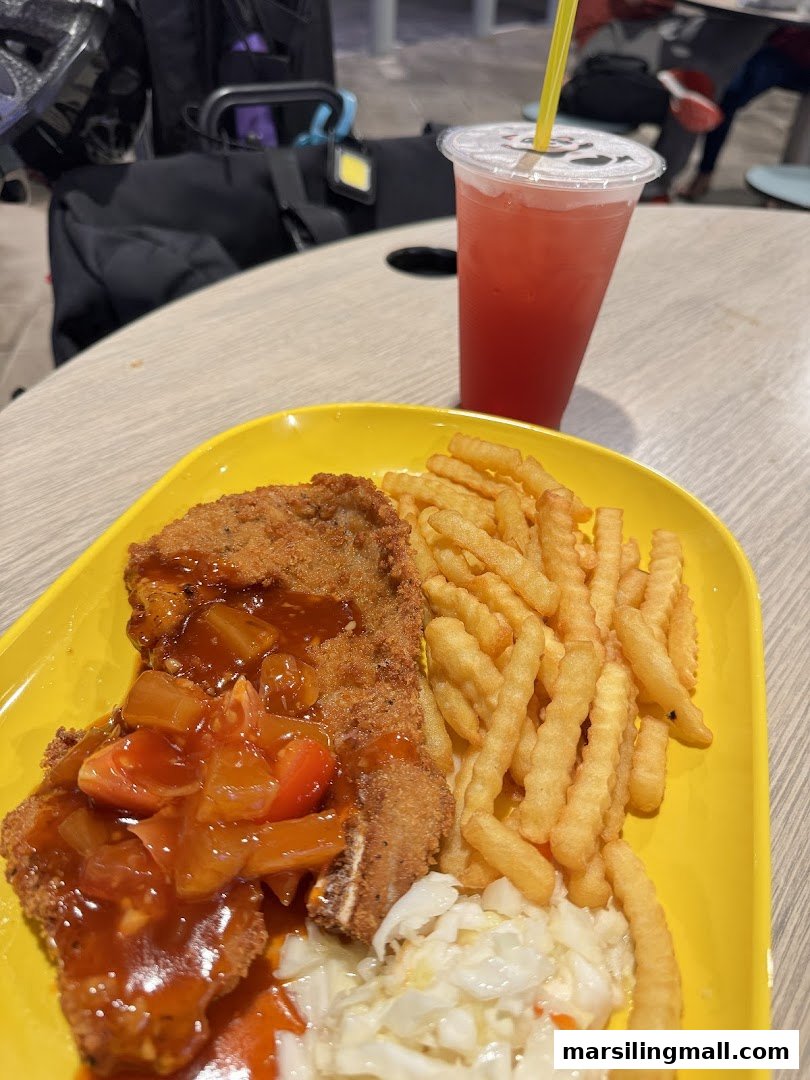 A delicious plate of fried pork chop with sweet and sour sauce, fries, and coleslaw, served with a drink.