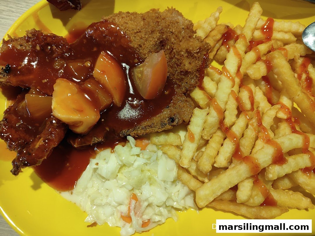 A vibrant yellow plate featuring fried chicken or fish with sweet and sour sauce, french fries, and coleslaw.