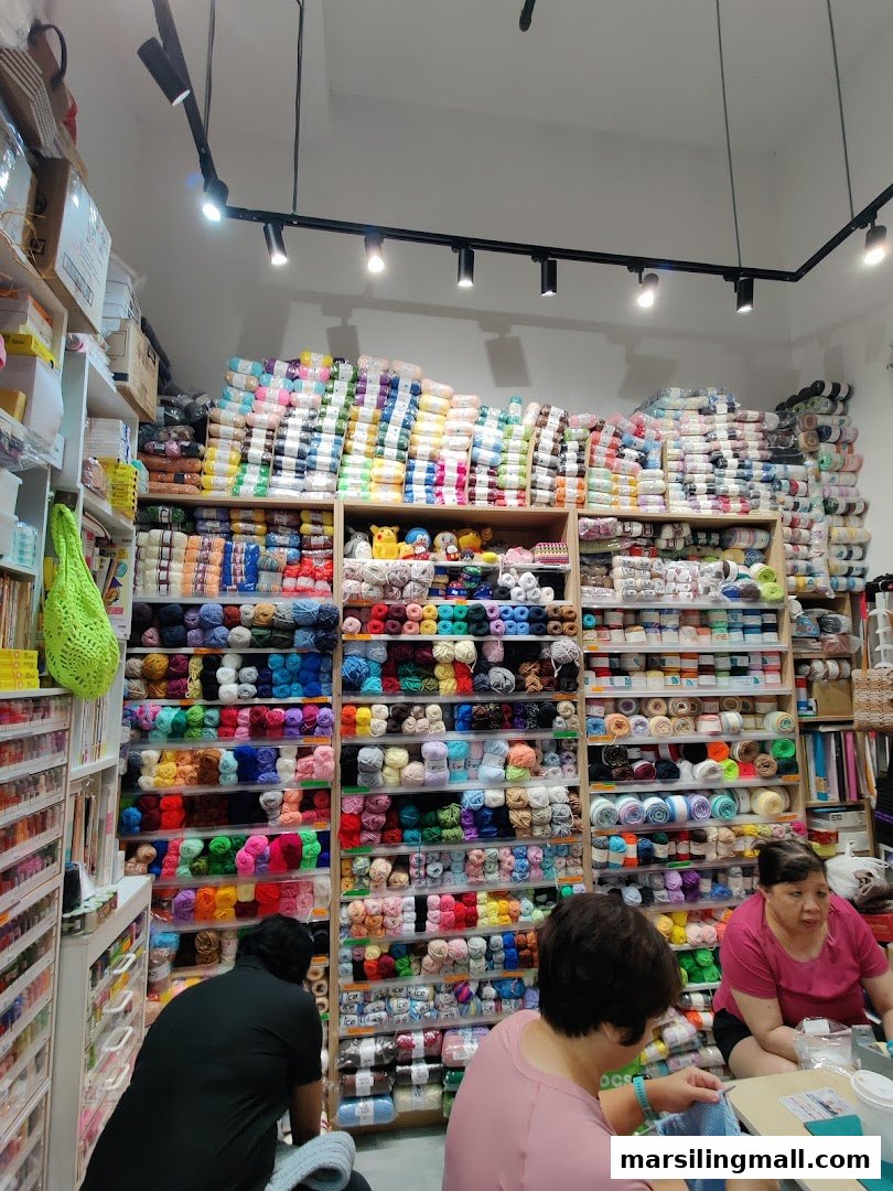 Vibrant craft shop interior showcasing shelves packed with colorful yarn and customers engaged in crafting.