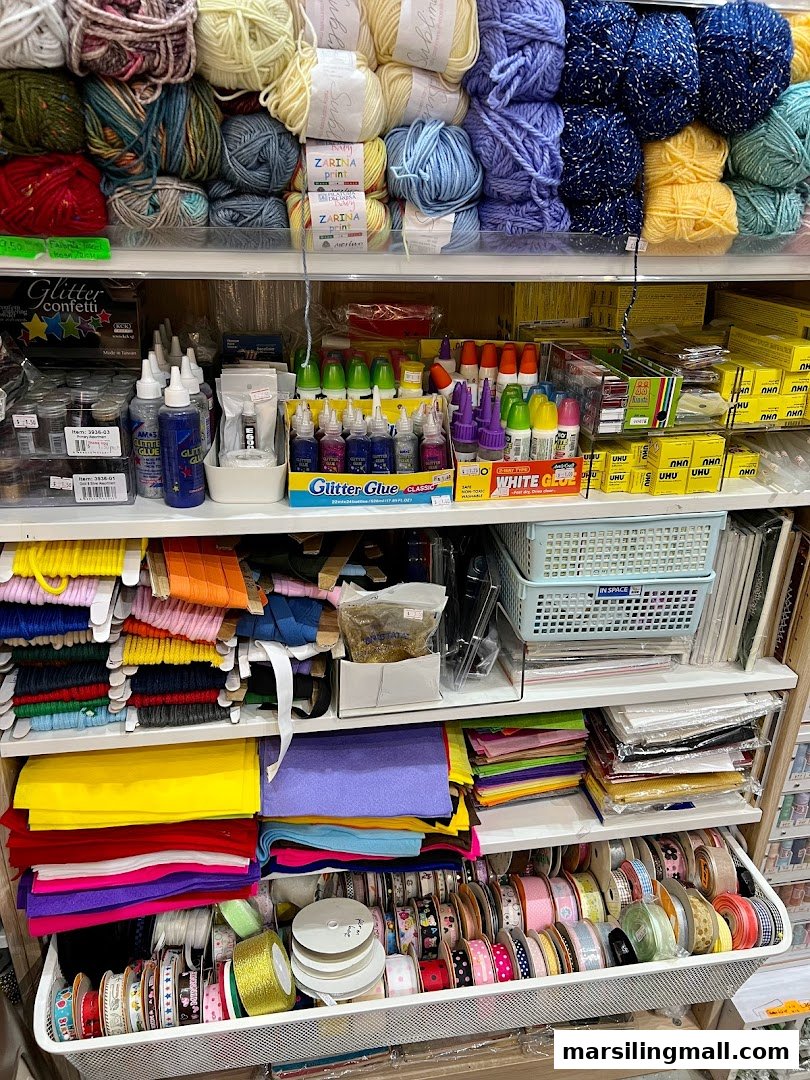 Shelves filled with colorful yarn, glitter glue, felt, ribbons, and various craft supplies.