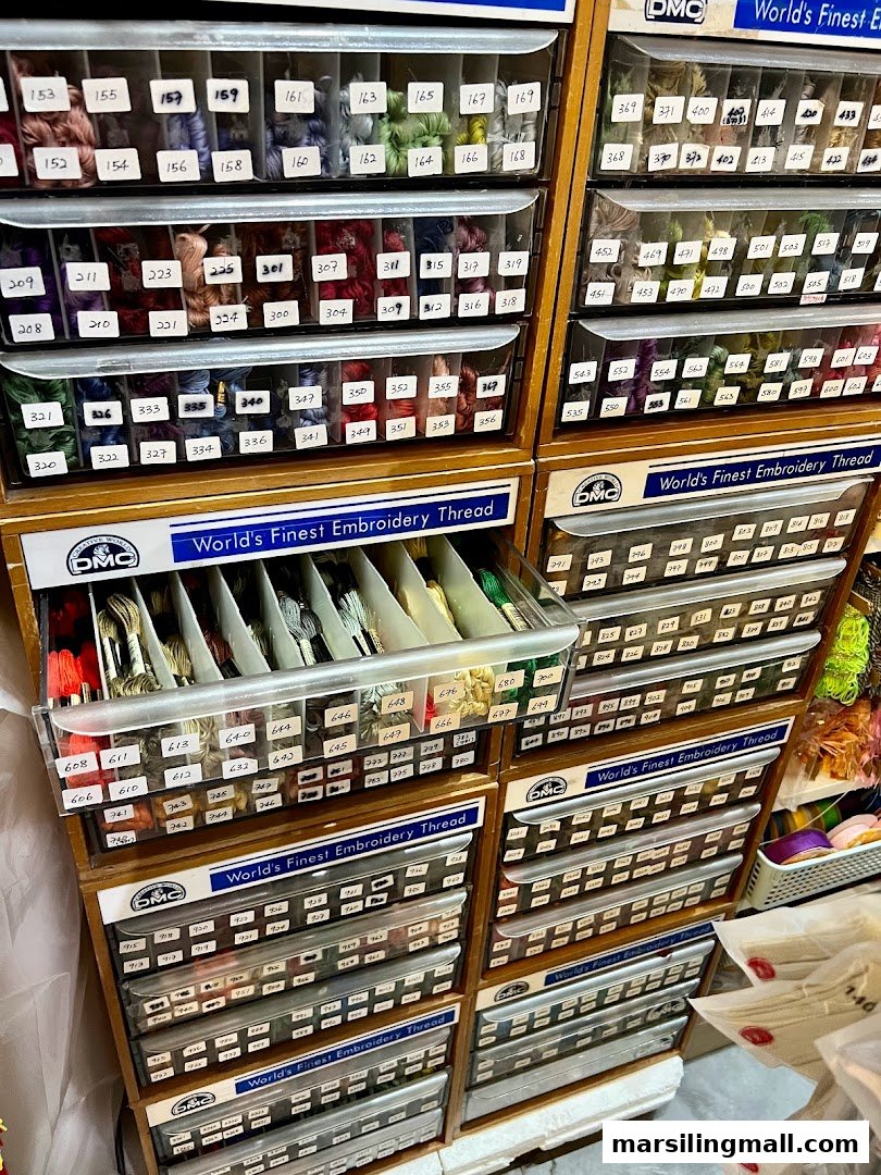 Close-up of organized drawers filled with a vast selection of colorful DMC embroidery threads.