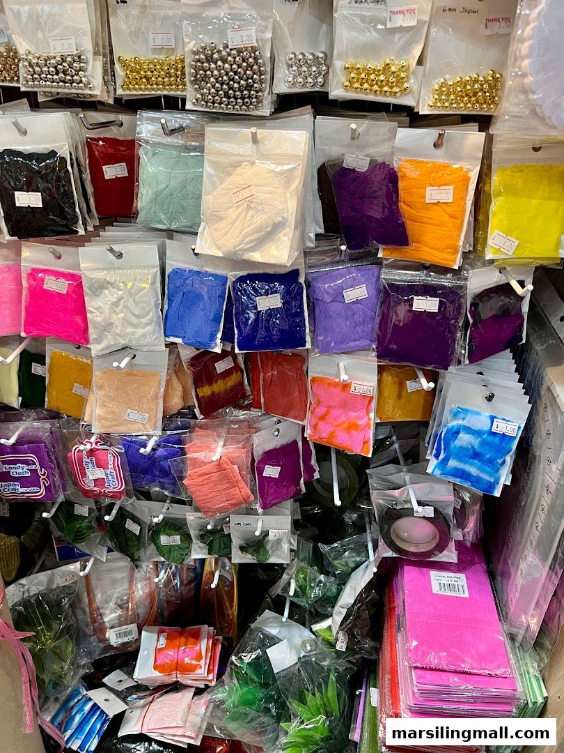 A vibrant display of packaged crafting supplies, including beads, fabrics, and decorative items, at Crafting House.