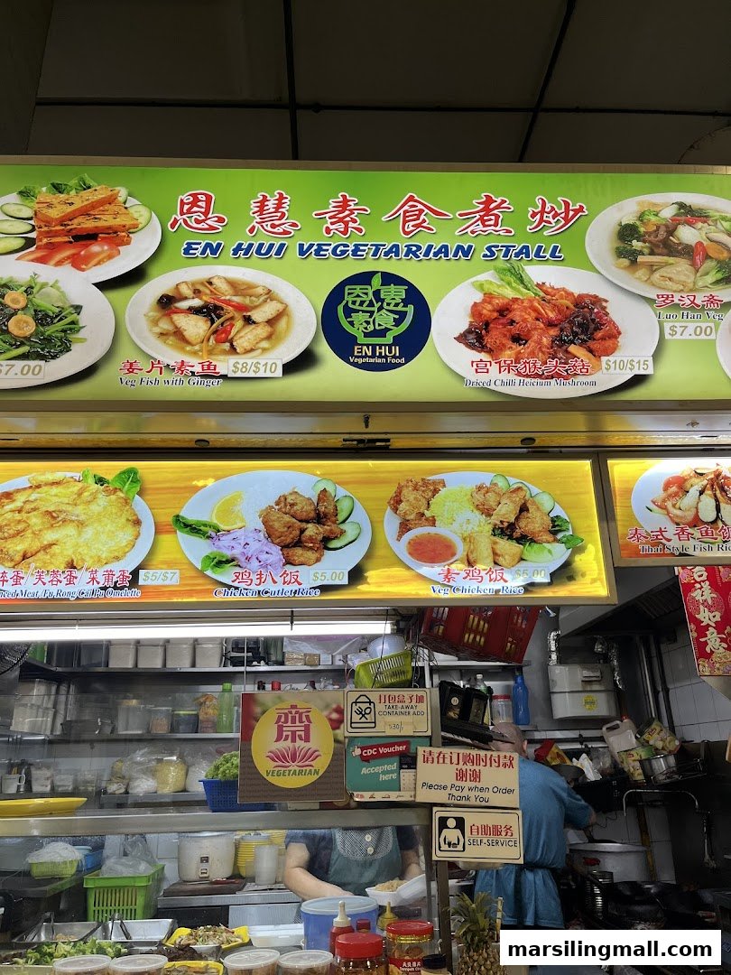 A vibrant display board showcasing various vegetarian dishes with prices at En Hui Vegetarian stall.