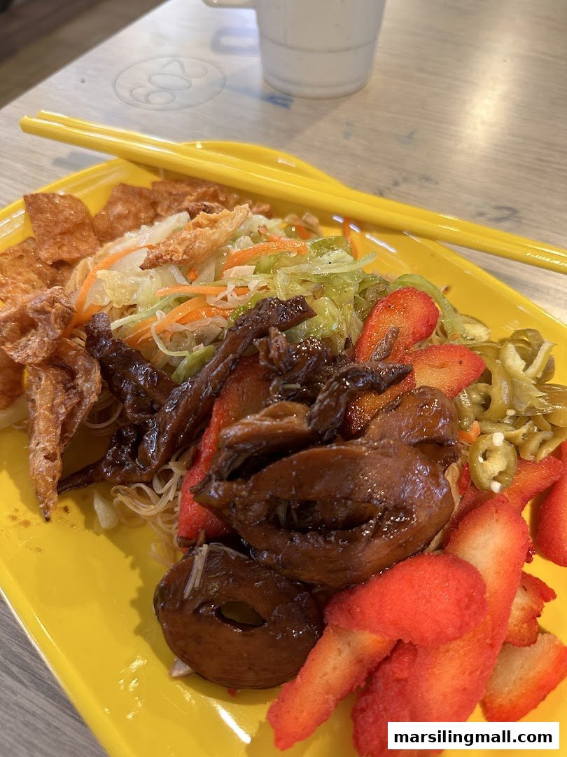 A vibrant plate of vegetarian noodles with various toppings and yellow chopsticks.