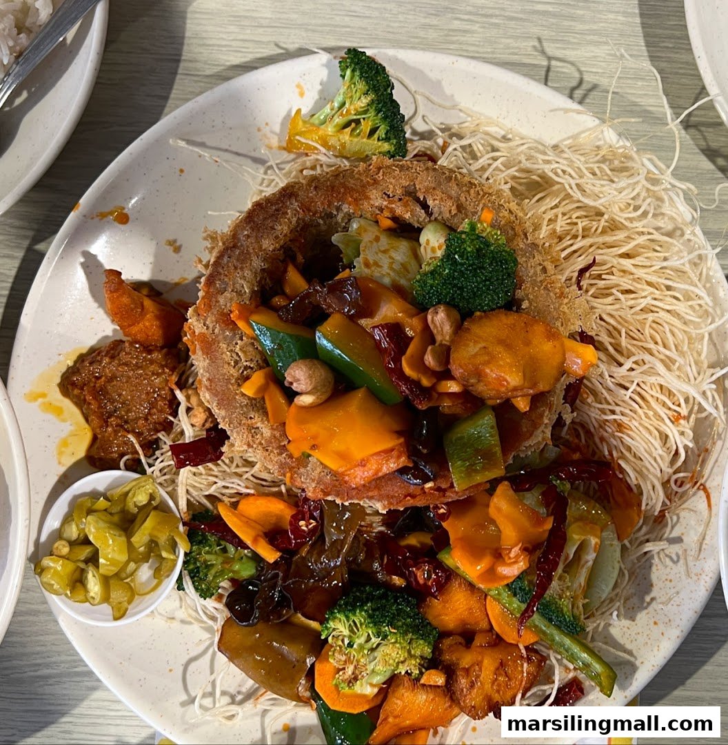 A vibrant vegetarian dish featuring a crispy taro ring filled with stir-fried vegetables and served on a bed of crispy noodles.