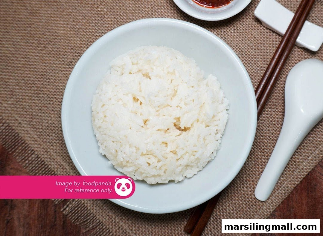 A bowl of perfectly steamed white rice, accompanied by chopsticks and a spoon.