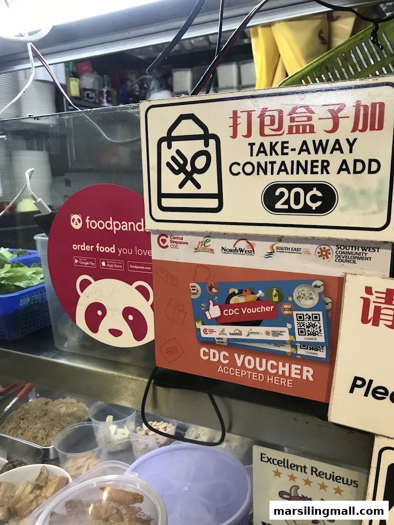 A food stall counter displaying signs for take-away container charges, Foodpanda delivery, and CDC voucher acceptance.