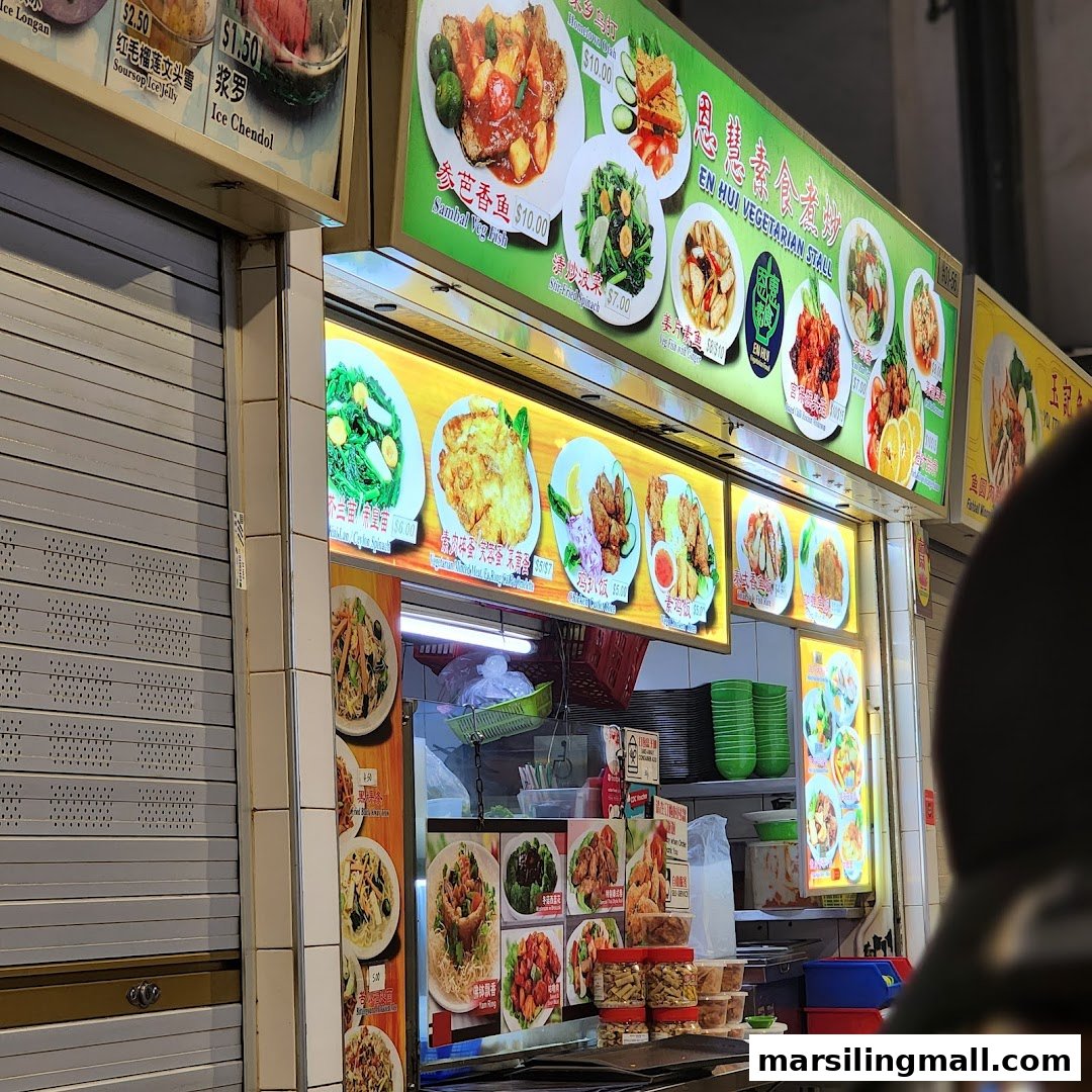 An illuminated display board showcasing various vegetarian dishes and prices at En Hui Vegetarian stall.