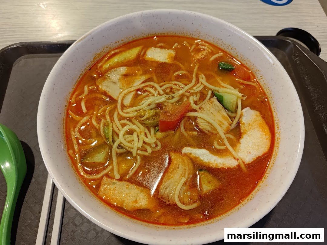 A vibrant bowl of vegetarian laksa noodles with various toppings and a green spoon.