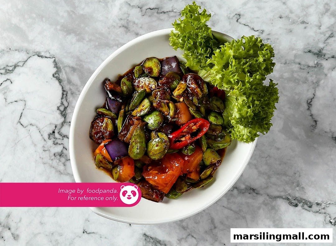 A vibrant vegetarian dish featuring petai, eggplant, and chili, served in a white bowl.