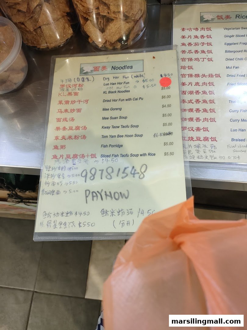 A close-up view of En Hui Vegetarian's menu board, displaying various noodle and rice dishes with prices.