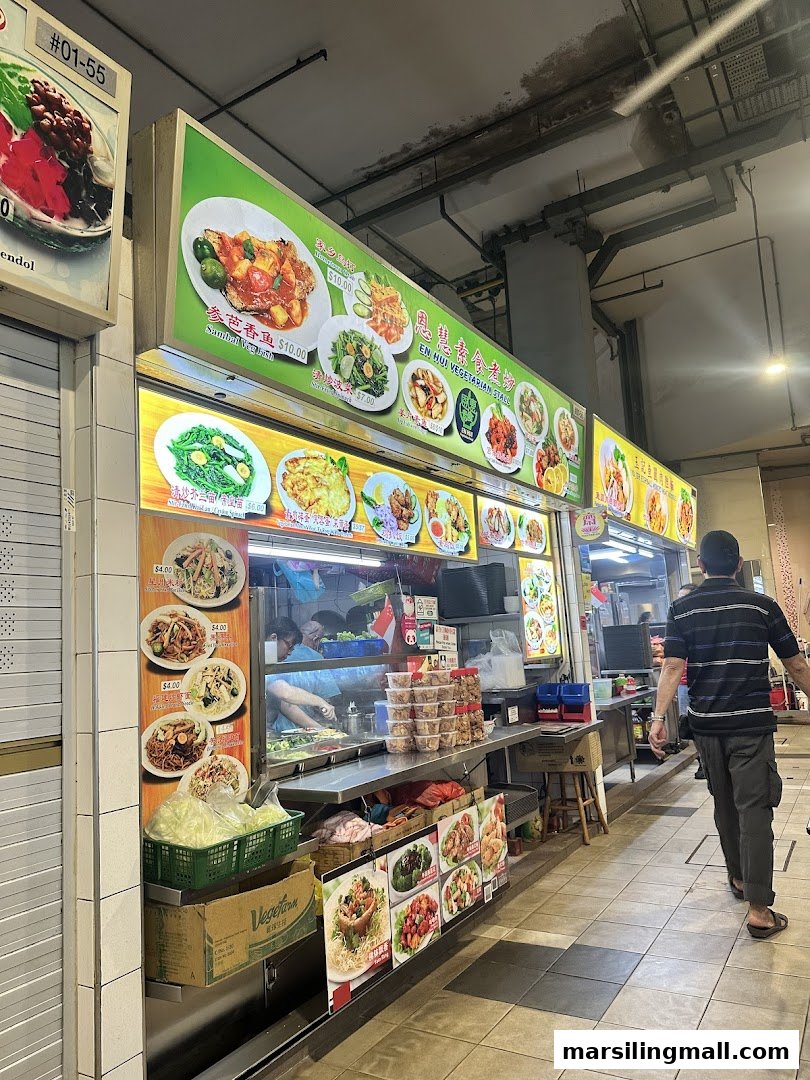 A bustling vegetarian food stall displaying a wide array of dishes and prices on large menu boards.