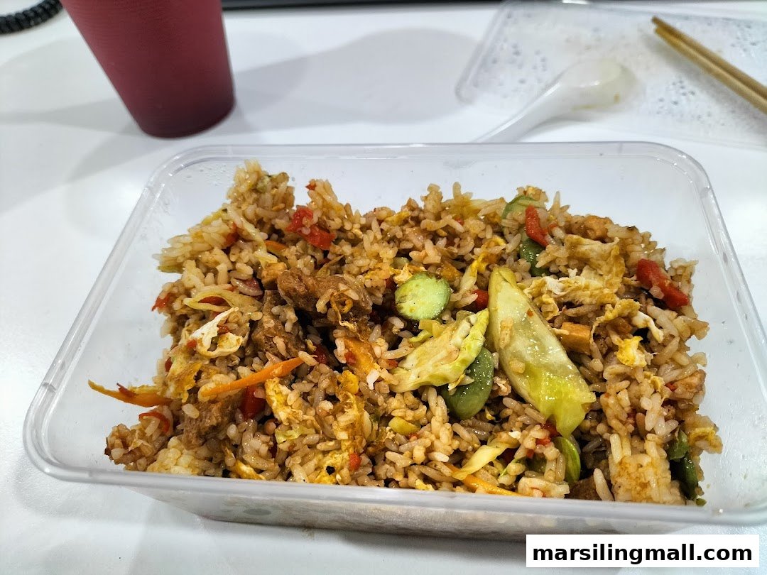 A clear plastic container of vegetarian fried rice with vegetables and egg, ready for takeaway.