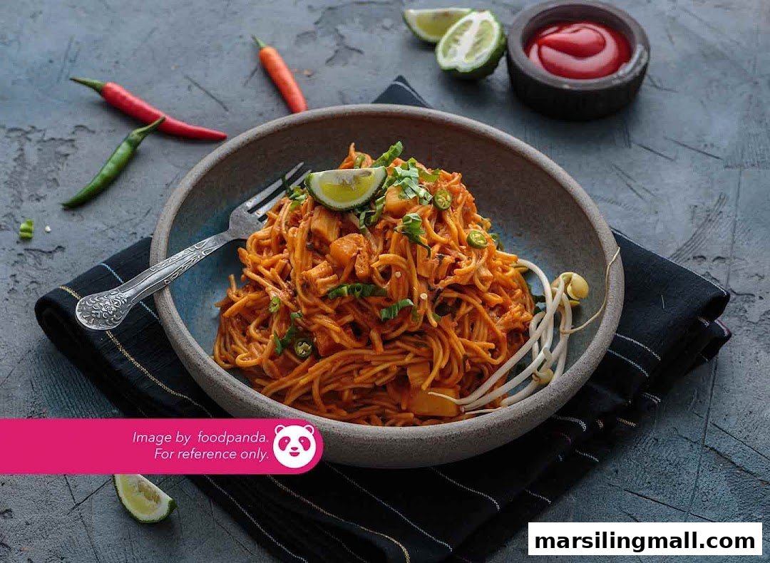 A vibrant bowl of vegetarian noodles garnished with lime, chili, and bean sprouts.