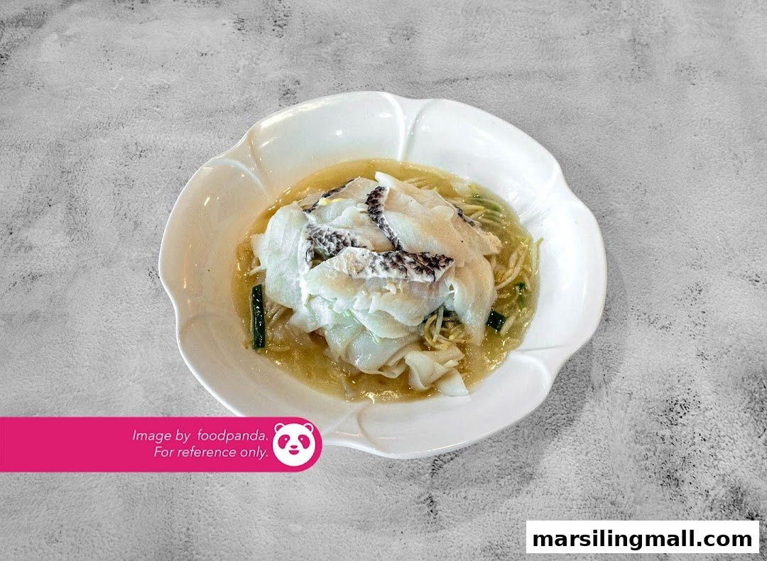 A white bowl filled with a vegetarian fish dish, noodles, and vegetables in a light broth.