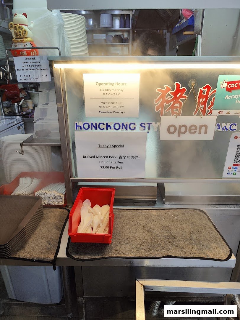 A counter display showing operating hours, a daily special, and customer notices at a Hong Kong style food stall.