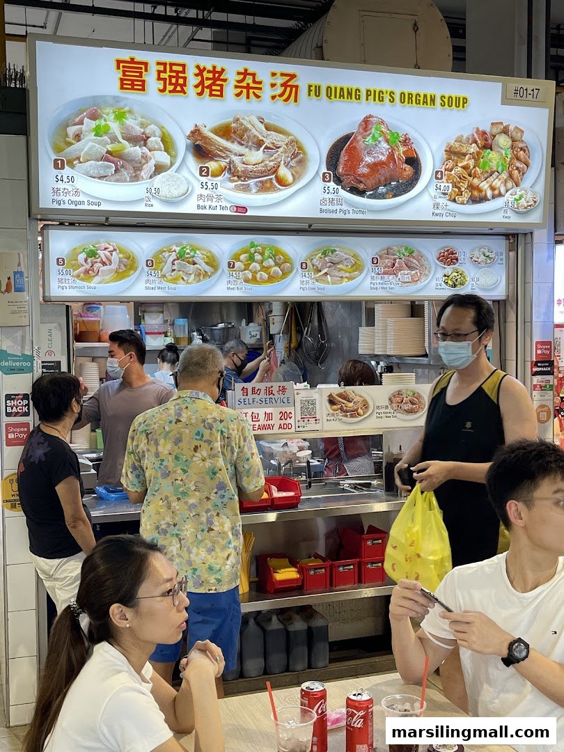 A bustling food stall with a large menu board, serving traditional Singaporean pig's organ soup and other dishes.