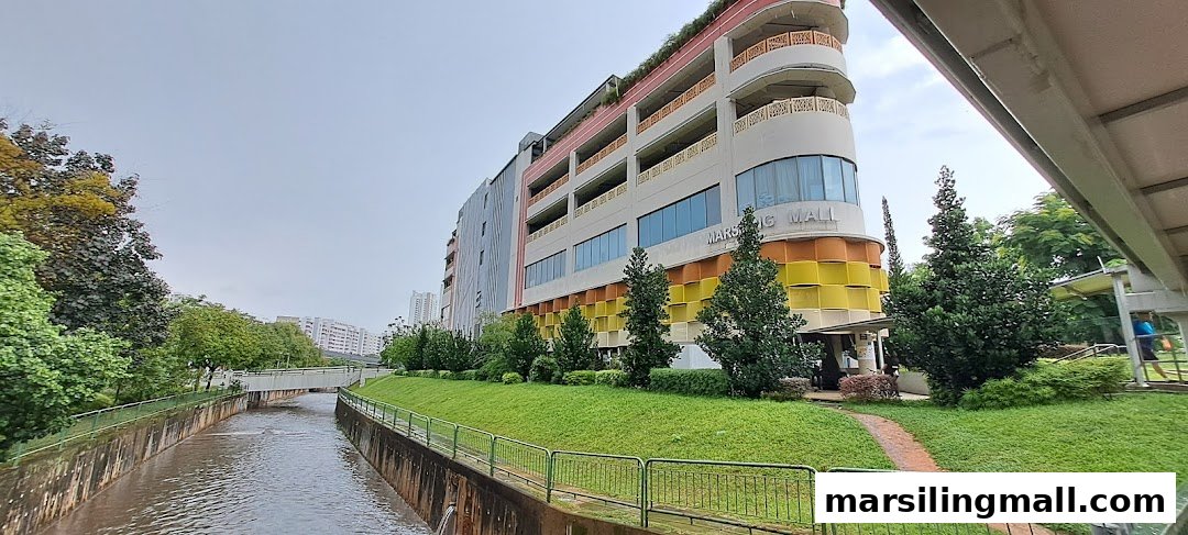 Exterior view of Marsiling Mall next to a canal with lush greenery.