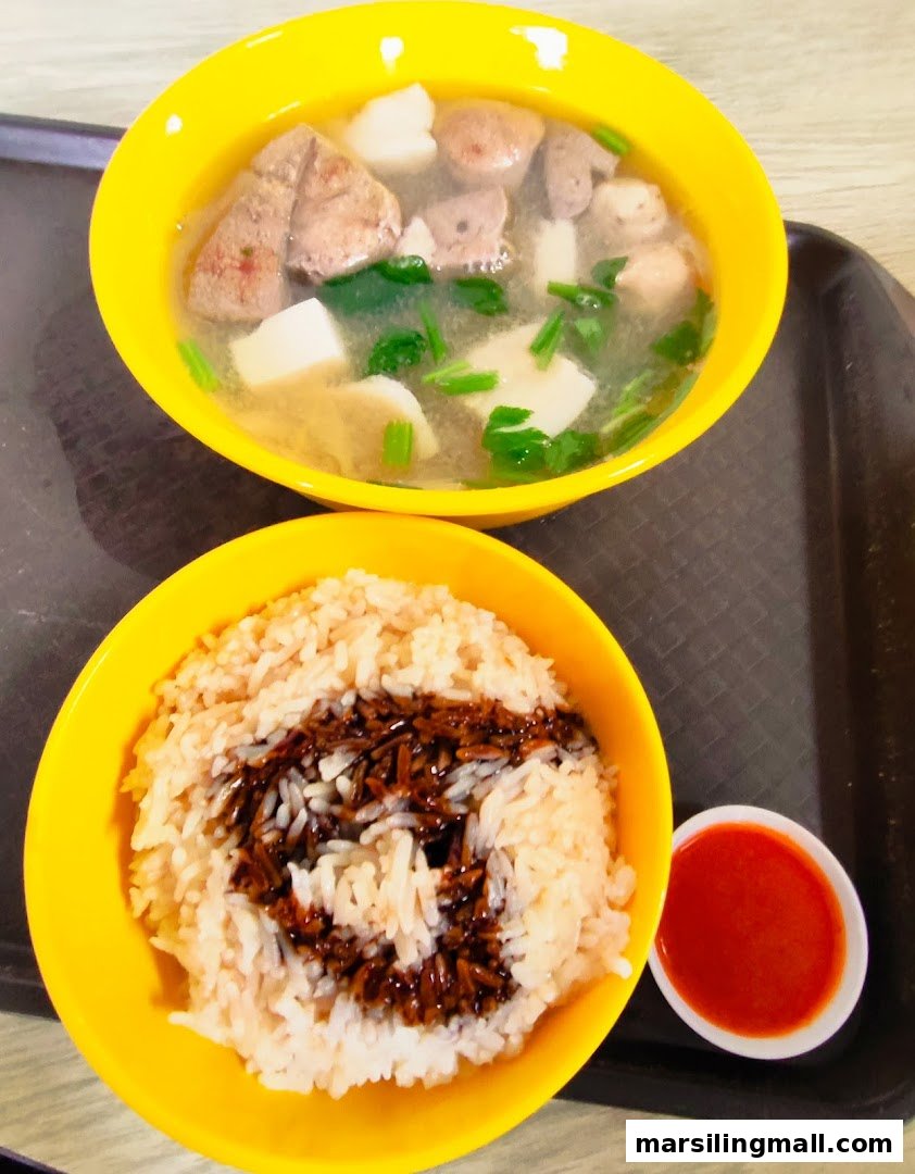 A comforting bowl of pig organ soup with rice and chili sauce on a tray.
