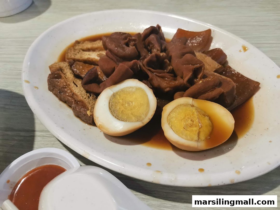 A plate of braised pig organs, tofu, and eggs in a savory sauce, served with chili.