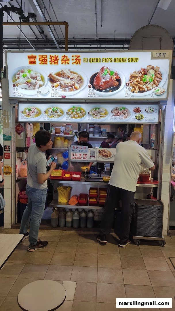 A bustling hawker stall, 'Fu Qiang Pig's Organ Soup', with its menu board and customers.