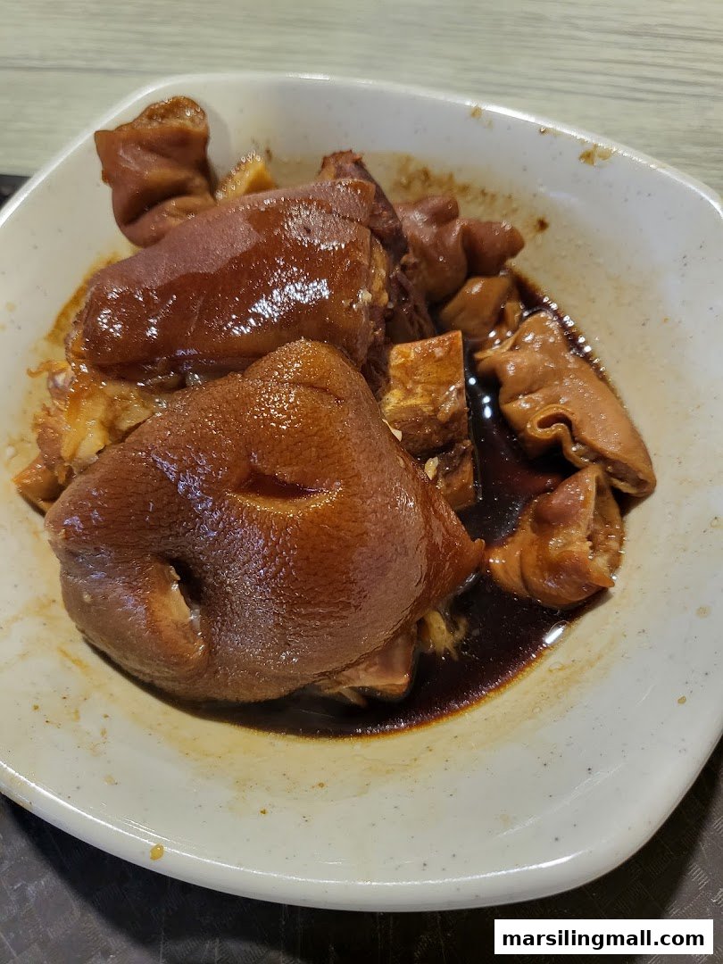 A bowl of glistening braised pig trotters and intestines in a rich, dark sauce.