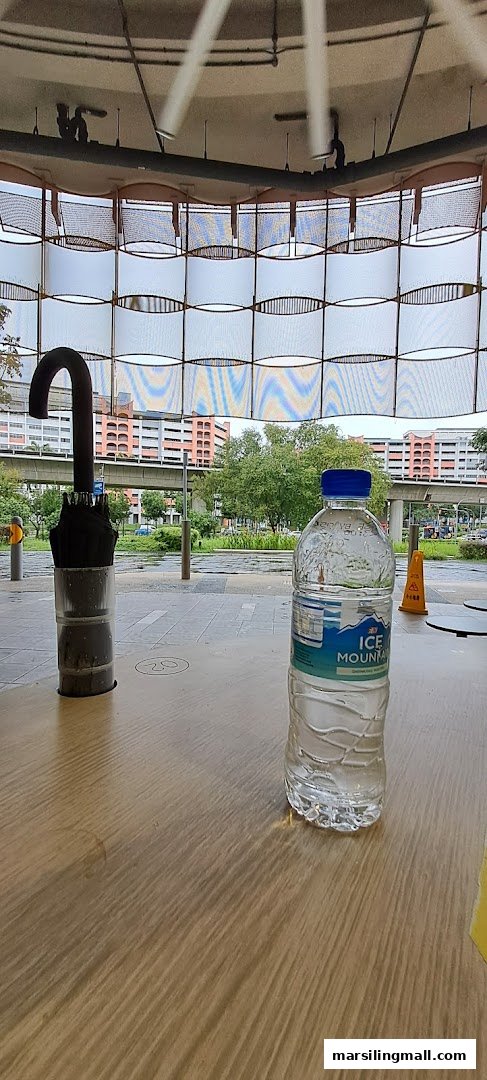 A table with an umbrella and water bottle, overlooking an urban landscape.