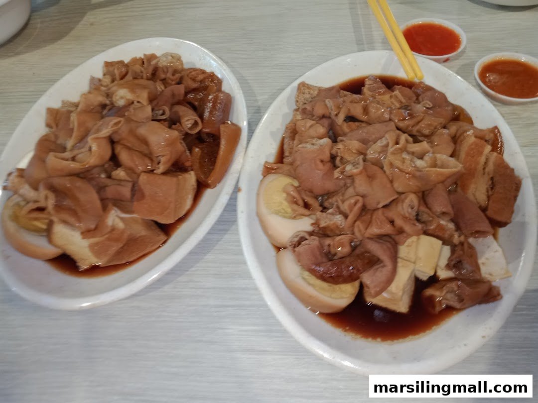 Two plates of braised pig organs, eggs, and tofu in a savory sauce, with chili dips.
