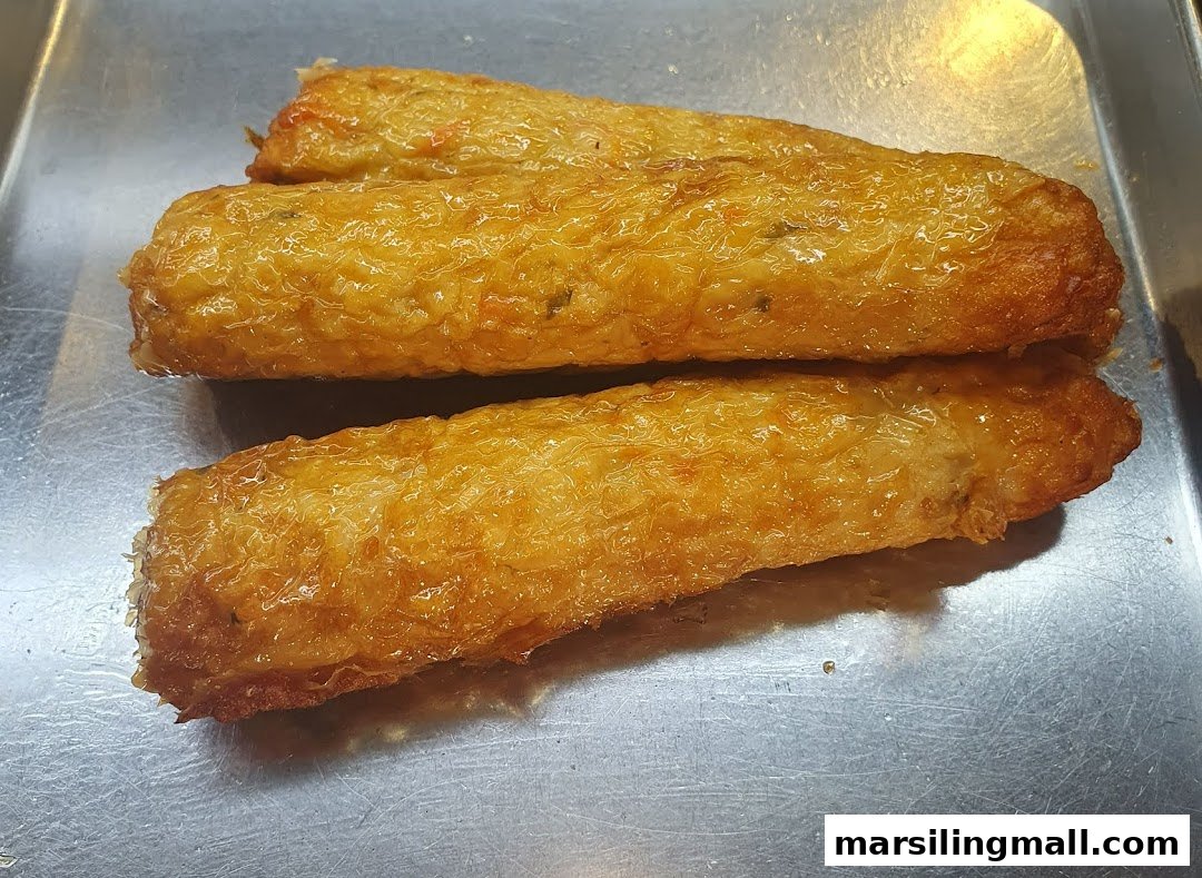 Three golden-brown fried rolls, possibly Ngoh Hiang or similar, resting on a metal tray.