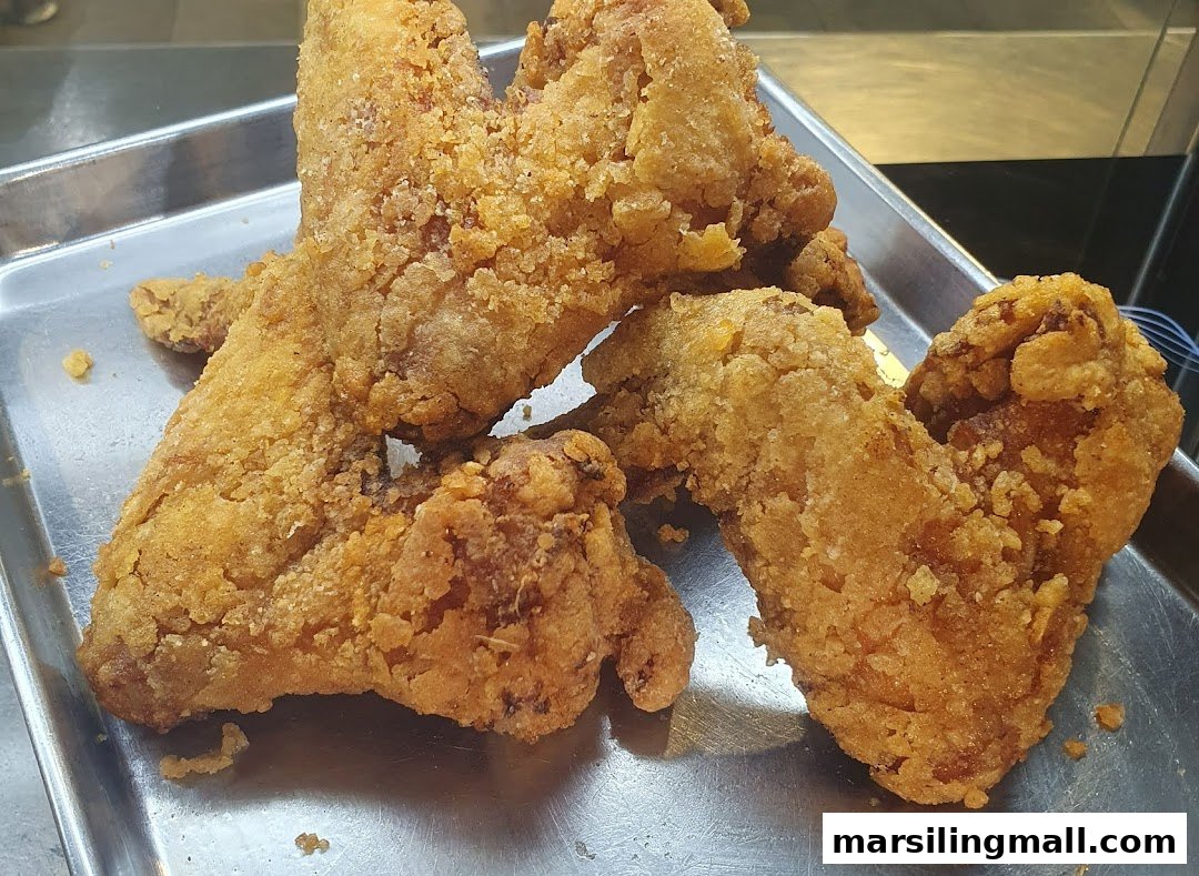 Close-up of several pieces of golden-brown fried chicken on a metal tray.