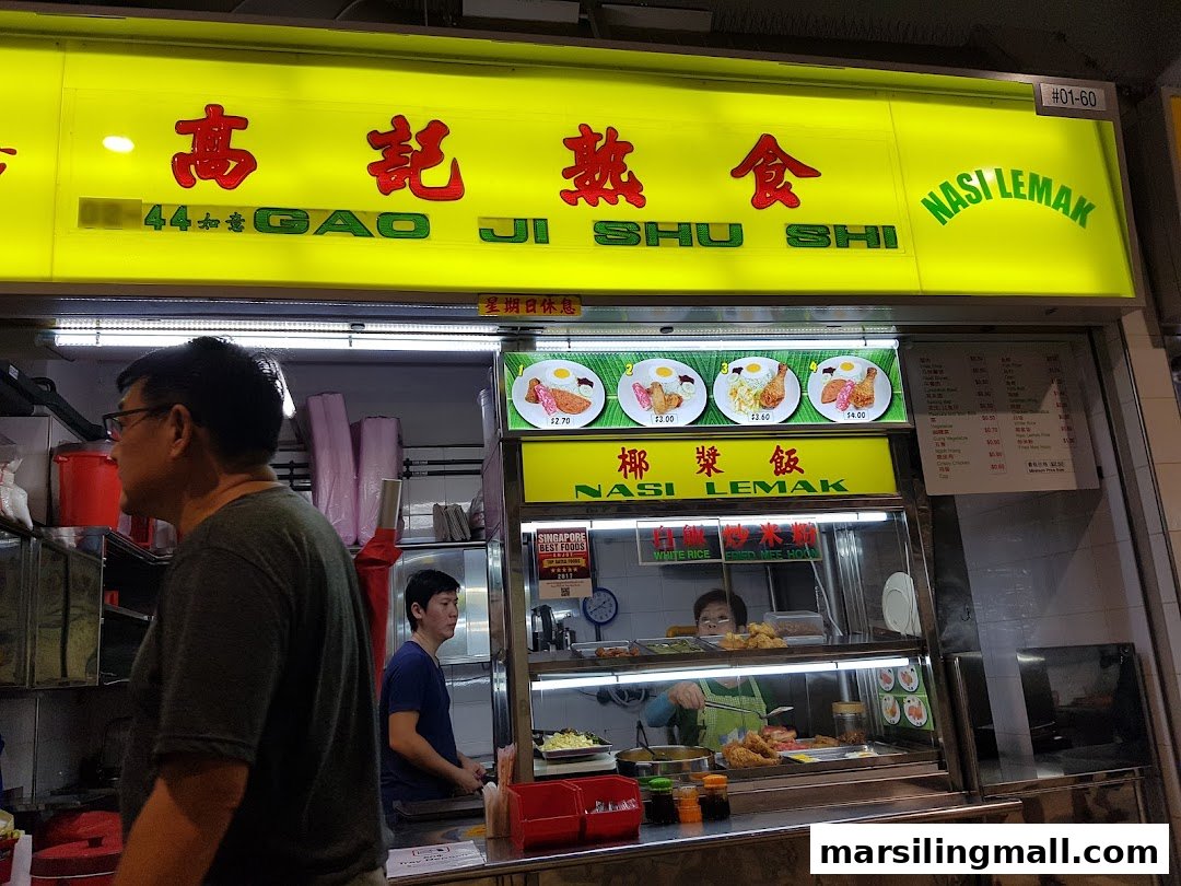 A vibrant food stall named Gao Ji Shu Shi Nasi Lemak, featuring a bright yellow sign and food display.
