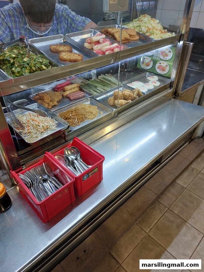 A vibrant display of various cooked dishes and ingredients at a food stall counter.
