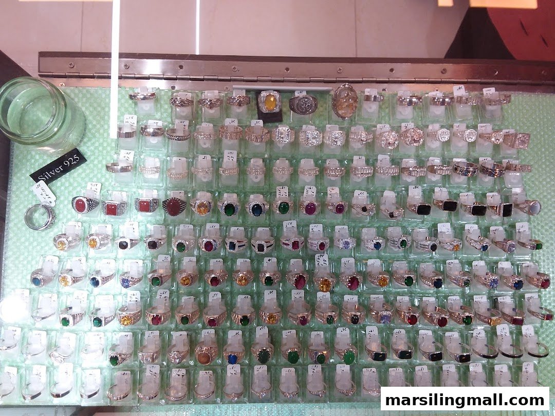 A close-up view of a display case showcasing a wide variety of silver rings, many adorned with colorful gemstones.