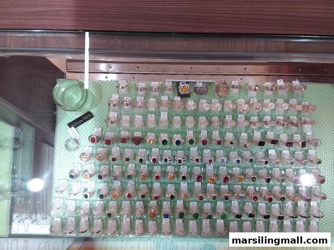 A display case filled with numerous 925 silver rings, many featuring colorful gemstones and intricate designs.