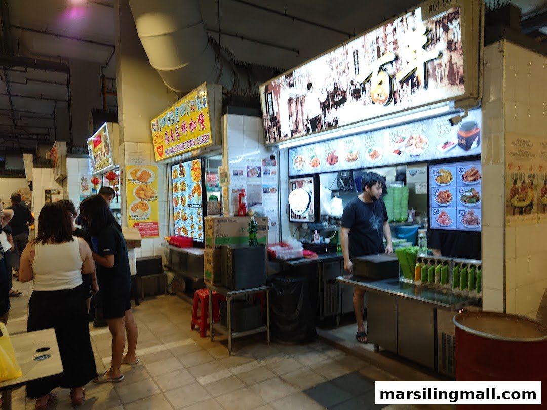 A bustling food stall, 'Hai Nan Hometown Curry', with staff and customers, showcasing various dishes.
