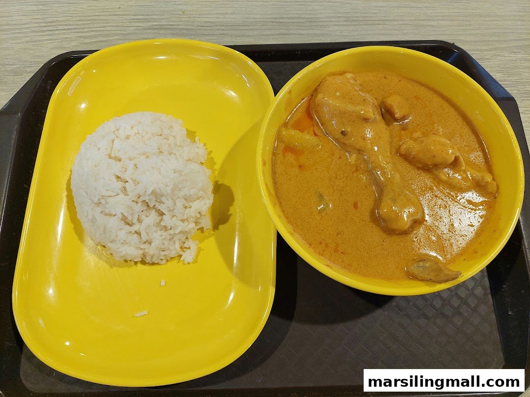 A vibrant yellow plate and bowl hold a serving of Hainanese curry chicken with white rice.